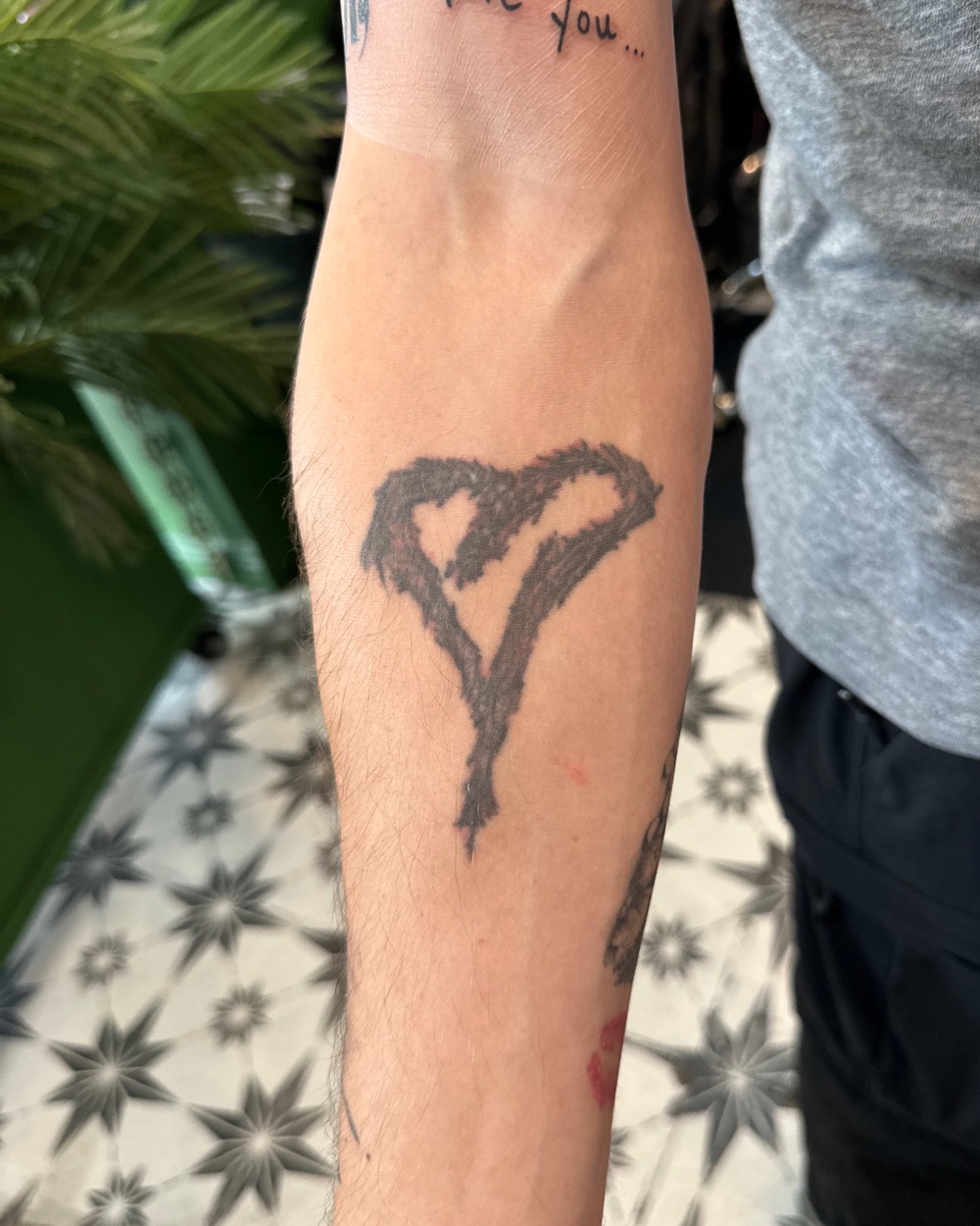 Before: rough black heart tattoo on forearm