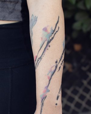 Abstract watercolor-style forearm tattoo