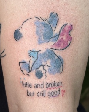 Colorful watercolor-style tattoo with 'little and broken, but still good' script